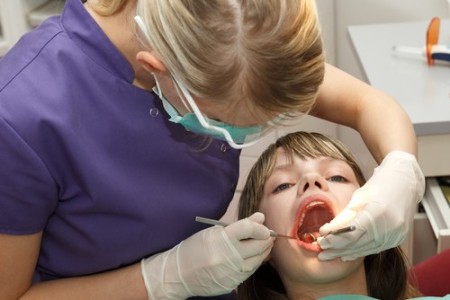 Dentista examina criança. Foto: Aigars Reinholds / Shutterstock.com