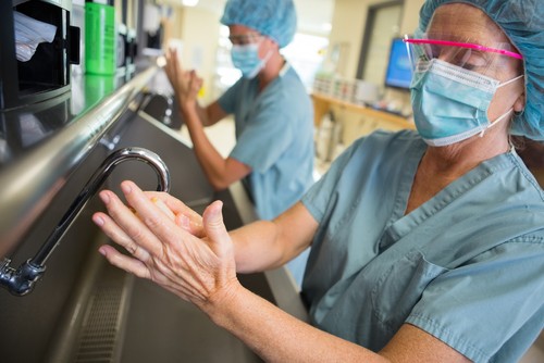 Foto de médico lavando as mãos para prevenir infecção hospitalar.